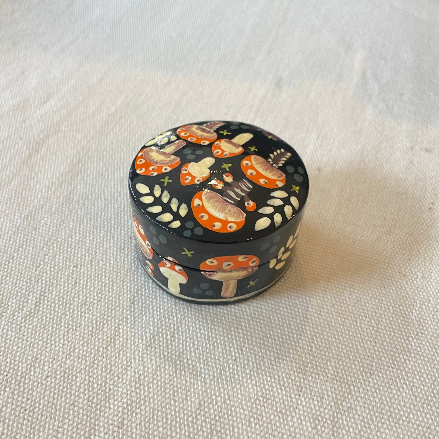 Glossy round toadstool box with lift-off lid, styled flat on fabric