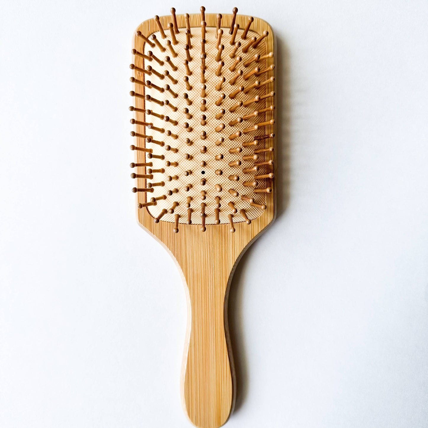 Eco-friendly bamboo hairbrush with wide bristles on a plain background