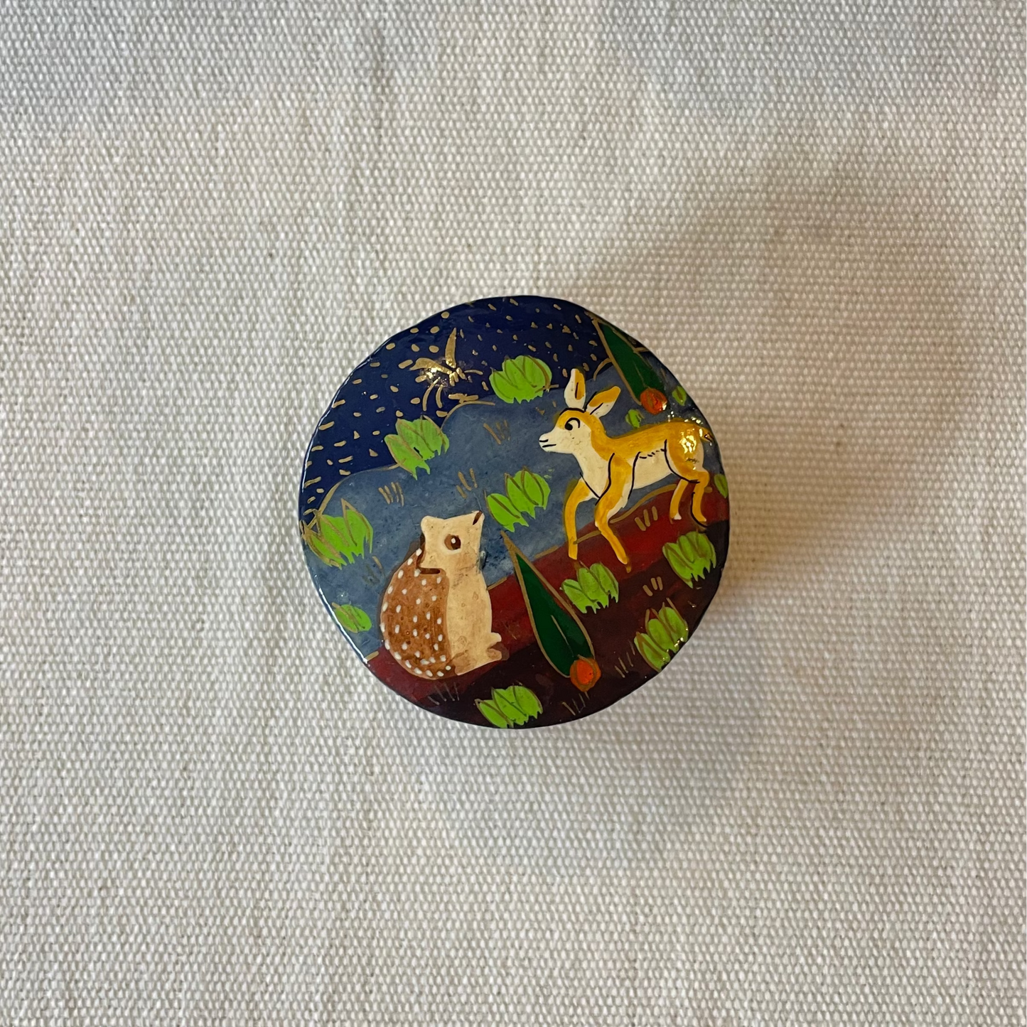 Round hand-painted trinket box with woodland animals design on plain linen background