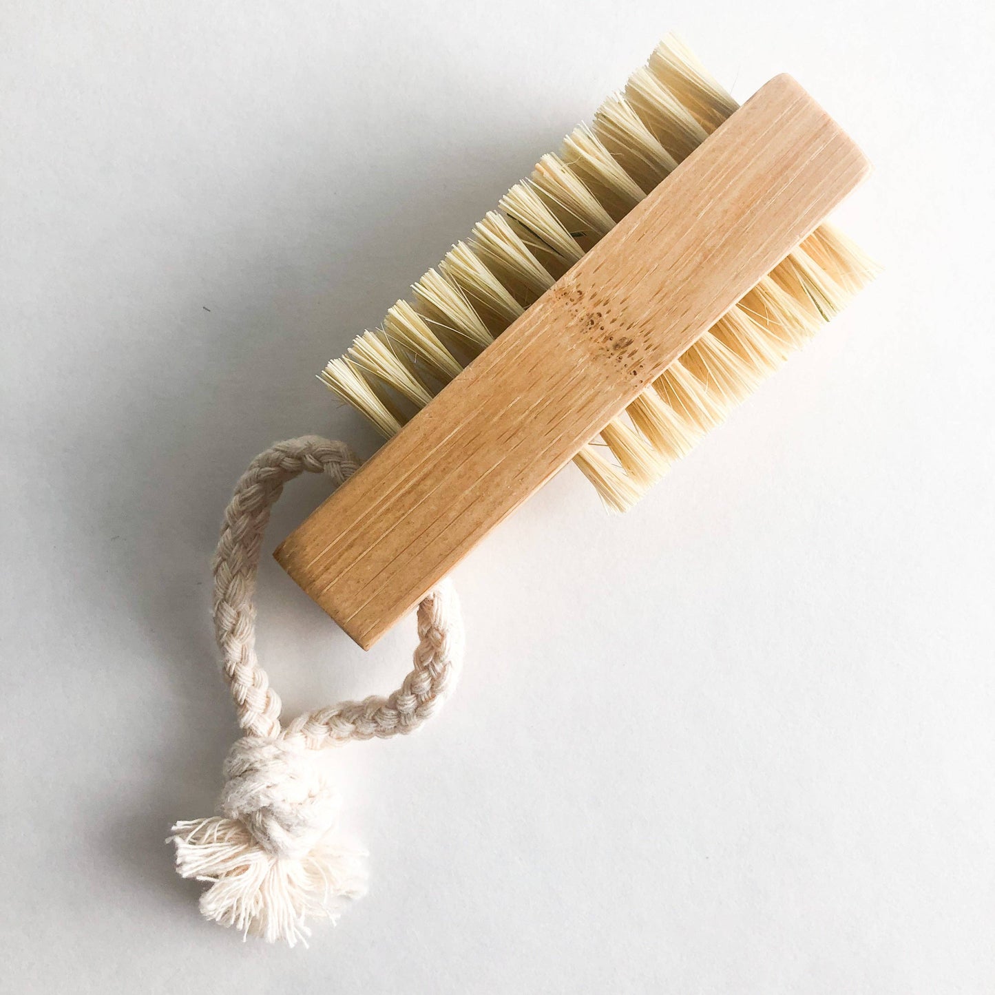 Close-up of natural bamboo nail brush showing textured bristles and rope loop