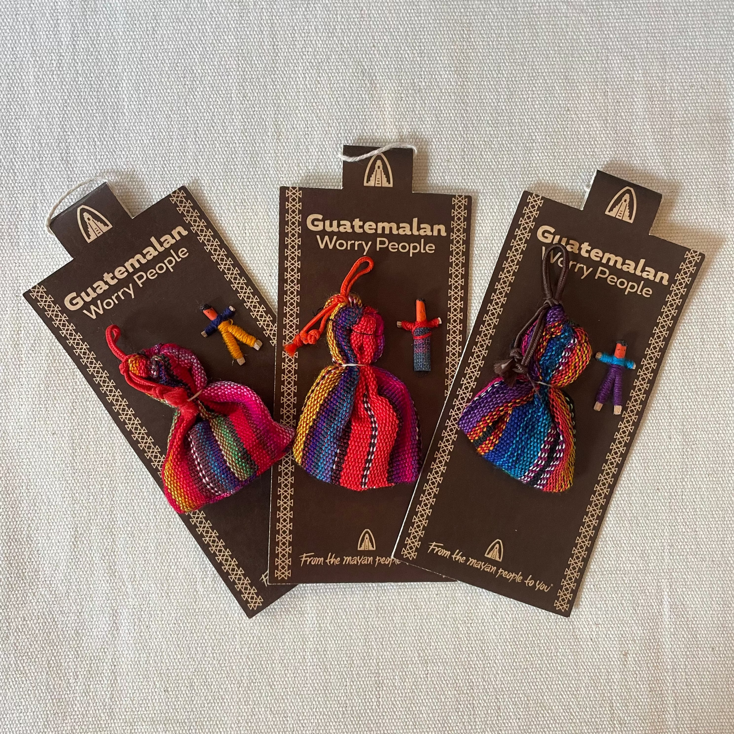 Set of six small colourful worry dolls displayed on card with bag, handmade in Guatemala